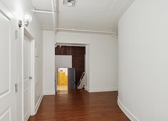 A long white hallway with a door at the end.