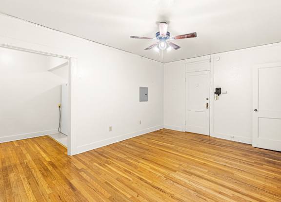 A room with a ceiling fan and wooden floors.