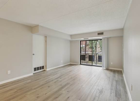 A room with wooden flooring and a sliding glass door.