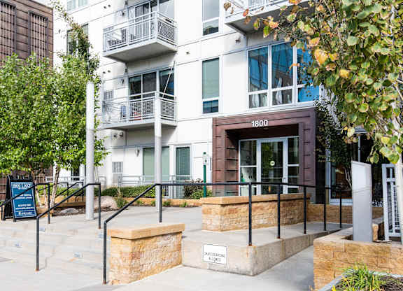 Modern building entrance with stone planters and landscaping at 1800 Lake Apartments, Minnesota