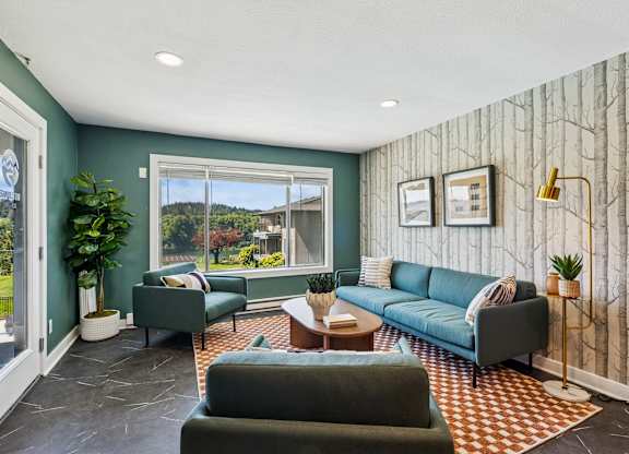 A living room with a green couch and a grey armchair.