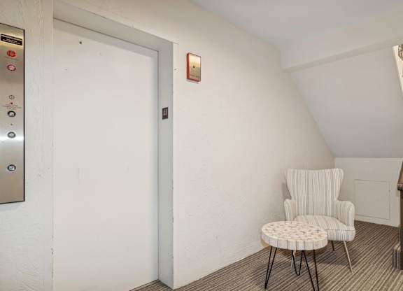 A white chair with a round back is placed in a room with a staircase.
