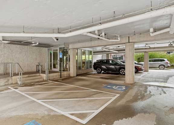 A parking garage with a car parked in a handicapped spot.