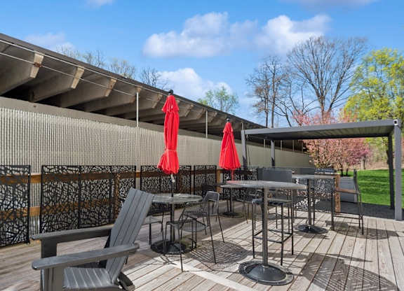A patio with a table and chairs under a red umbrella.