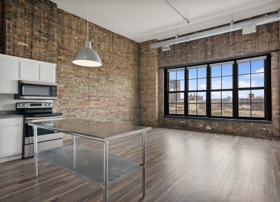 an open kitchen and dining area in an apartment with brick walls and a large windowat Gaar Scott Historic Lofts, Minnesota, 55401