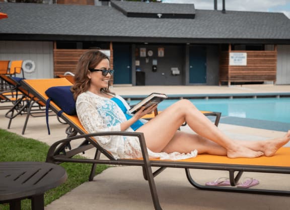 a woman sitting on a chaise lounge by a pool with a tablet in her hand at The Township at St. Charles, Illinois, 60174