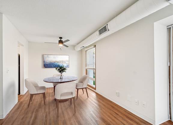 A room with a round table and chairs and a ceiling fan.