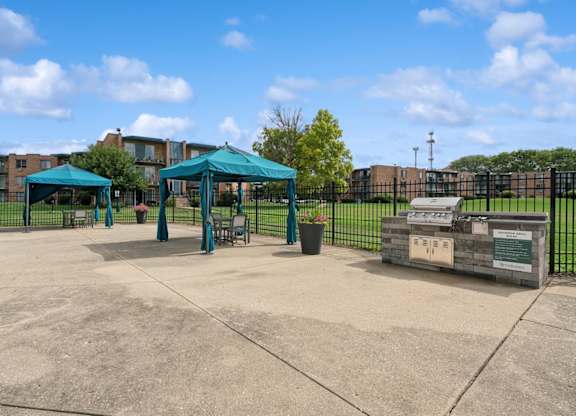 A playground with a green canopy and a sign on a wooden post.