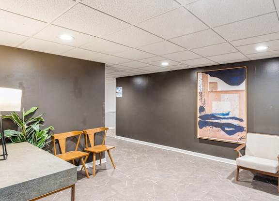 A room with a grey floor and a painting on the wall.