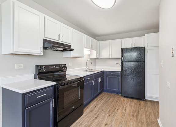 A kitchen with white and blue cabinets and a black stove top oven.