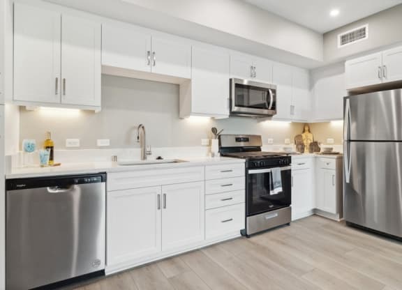 a large kitchen with white cabinets and stainless steel kitchen appliances at Arrive Temecula