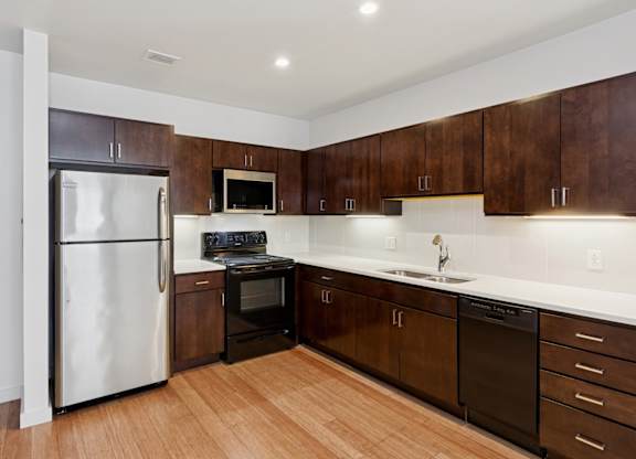 A kitchen with dark wood cabinets and a white counter top.