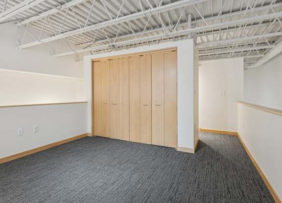 A room with a grey carpet and a wooden door.