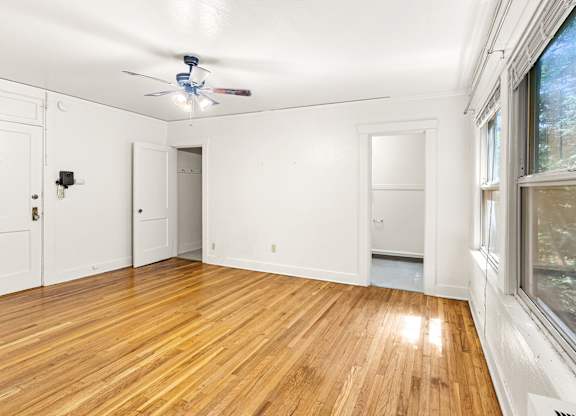 A room with a ceiling fan and wooden flooring.