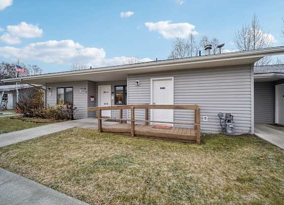 A house with a grey siding and a brown porch.
