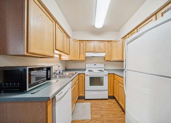 A kitchen with wooden cabinets and white appliances.