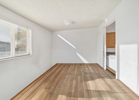 A room with wooden flooring and a window with blinds.