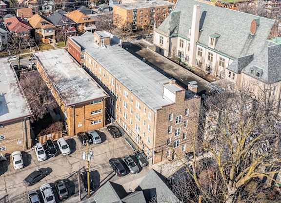 A parking lot with cars and a building in the background at Pleasant Oak Apartments, Oak Park, IL, 60302