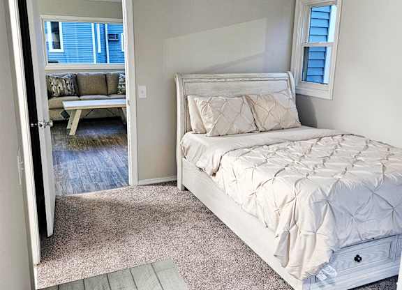A bedroom with a large bed with a view to the living room