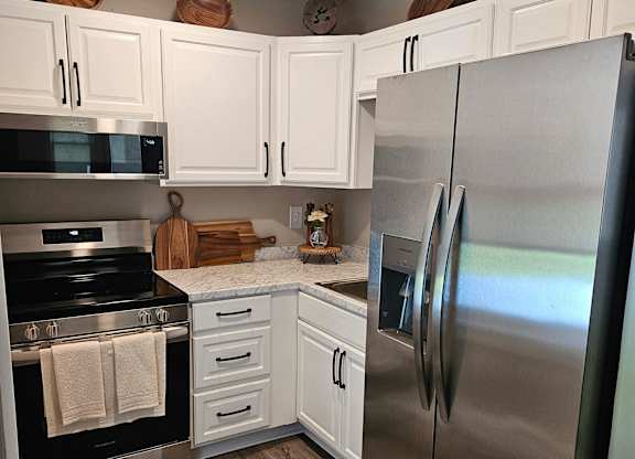 A modern kitchen with a stainless steel refrigerator and white cabinets.