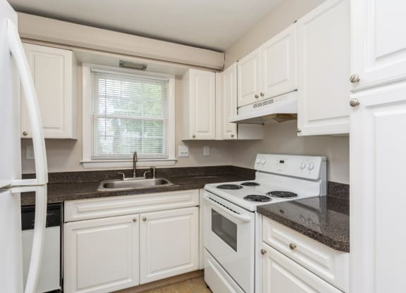 a kitchen with white appliances and granite counter tops and white cabinets