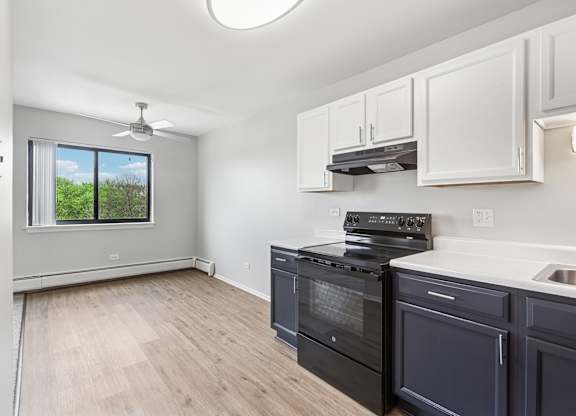 A kitchen with a black oven with white and blue cabinets.