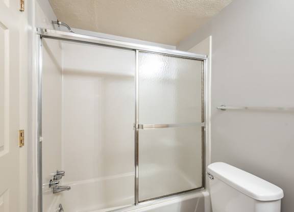 A white toilet sits next to a glass shower door in a bathroom.