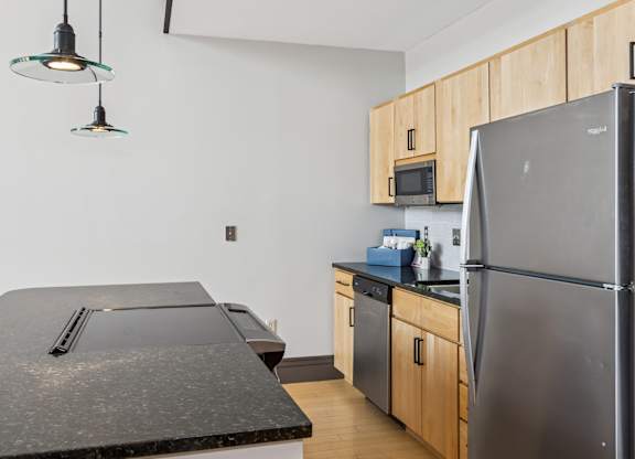 A kitchen with a black counter top and a black refrigerator.