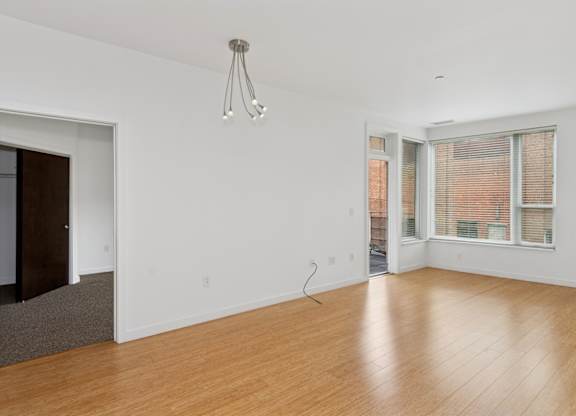 A room with wooden floors and a window with blinds.