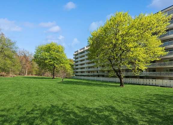 A large grassy field with trees and a building in the background.