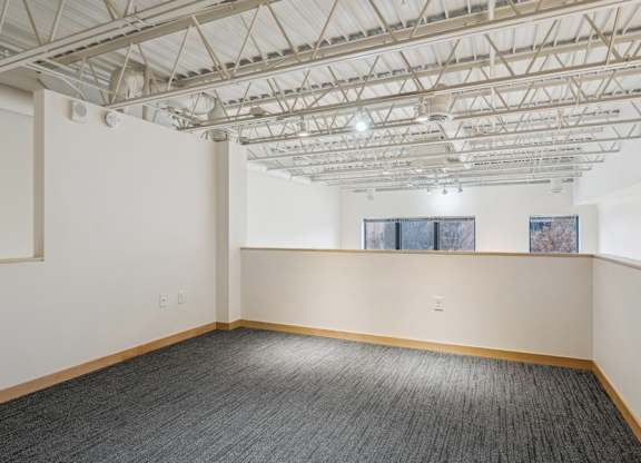 A room with a grey carpet and a white ceiling with a window.