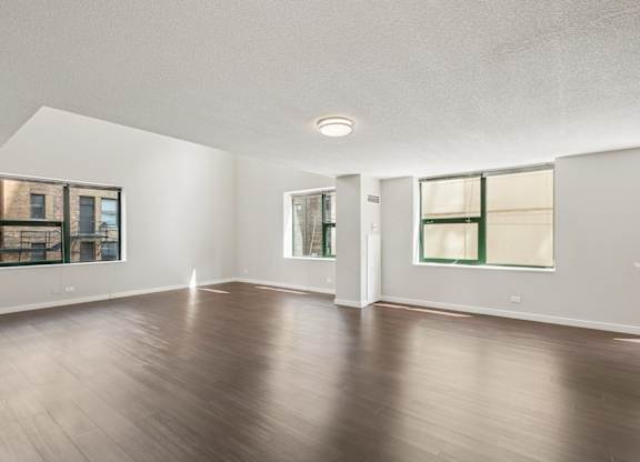 A spacious room with wooden floors and white walls.