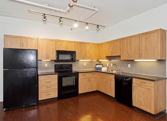 A kitchen with black appliances and wooden cabinets.