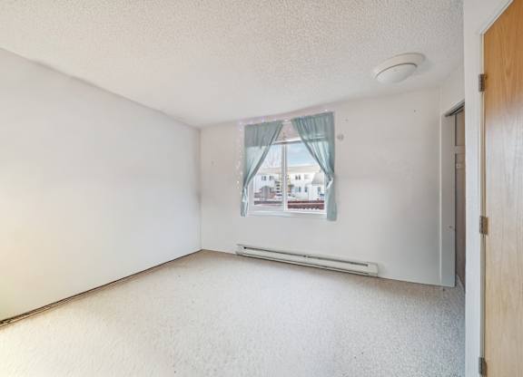 A room with a window showing a building outside.
