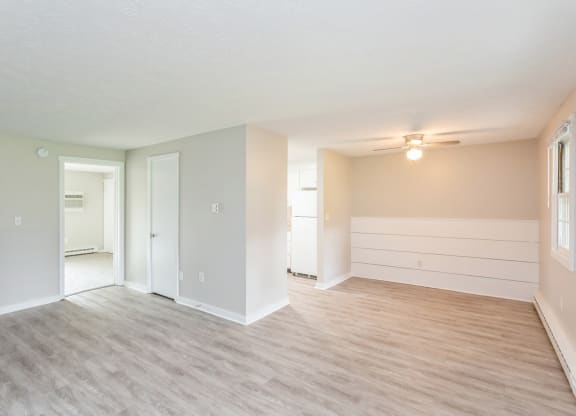 the living room and dining room of an empty apartment with wood floors and white walls at Stonebridge, Ellington