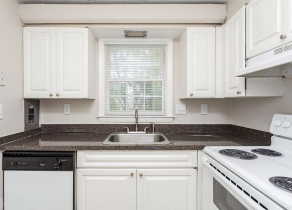 a kitchen with white appliances and granite counter tops and white cabinets