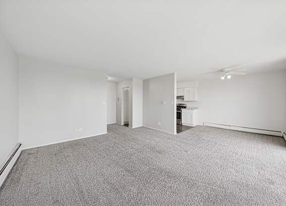 A spacious, empty room with grey carpeting and white walls.