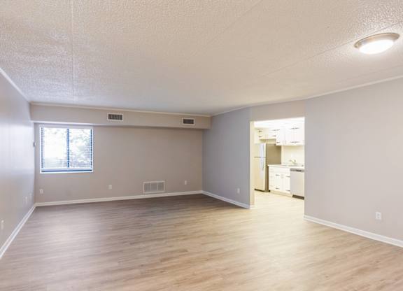 A spacious living room with wooden flooring and a window.
