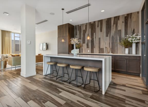 a kitchen with wooden floors and a bar with three stools at The Rowe, Grand Rapids