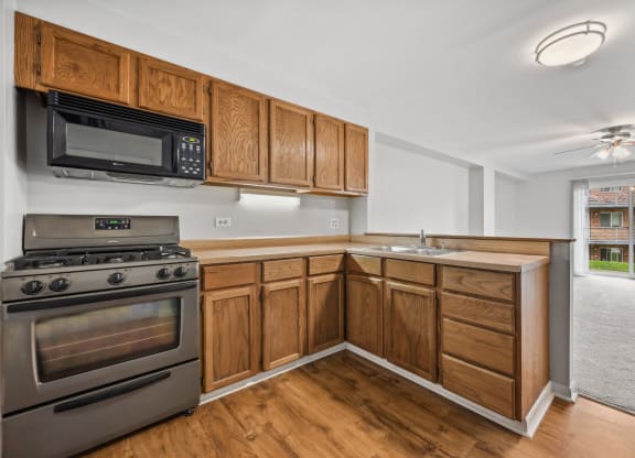White interior with wooden cabinets and black appliances at River Oaks, North Aurora, 60542
