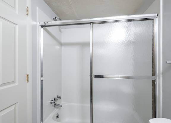 A white door with a silver handle and a white toilet in a bathroom.