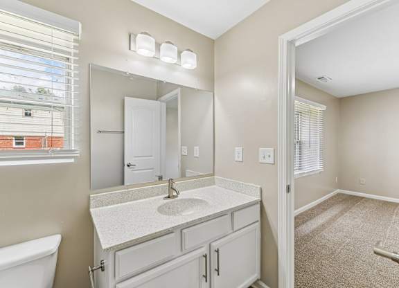 A bathroom with a white sink and a window with blinds.