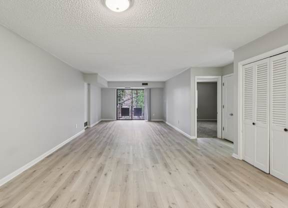 A long, empty room with wooden floors and white walls.