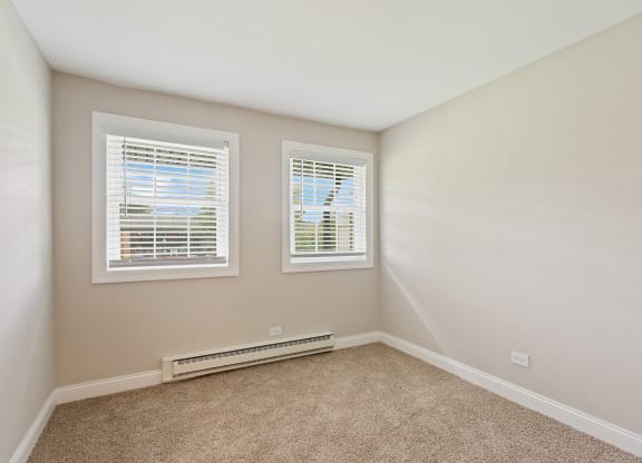 a bedroom with two windows and a carpeted floor at The Hinsdale, Hinsdale