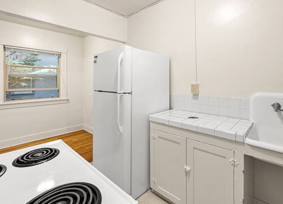A white fridge in a kitchen with a white tiled wall.