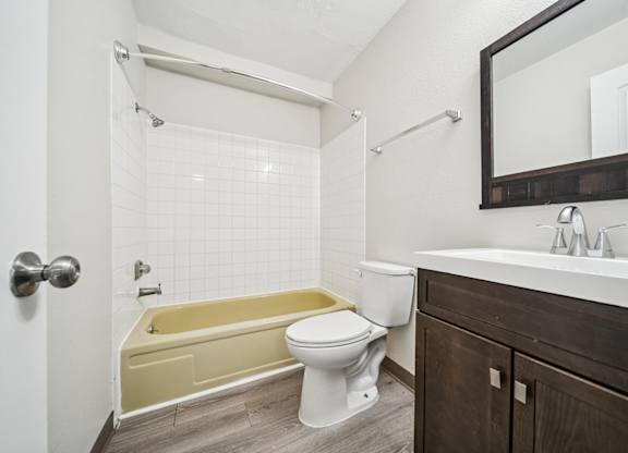 A white toilet sits next to a yellow bathtub in a bathroom.