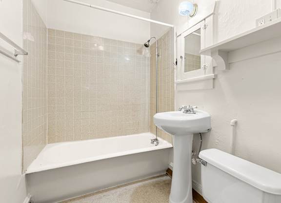 A white bathroom with a tub, sink, and toilet.