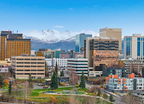 A cityscape with buildings and snow-capped mountains in the background.