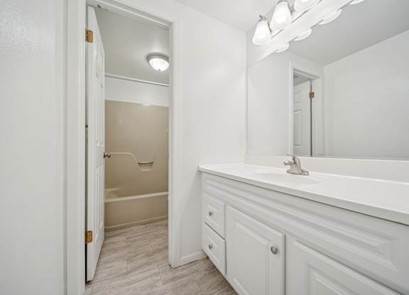 A white bathroom with a tub, sink and mirror.