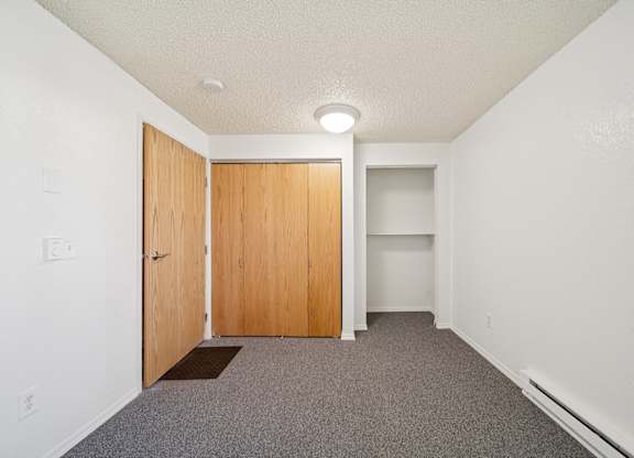 A room with a brown mat on the floor and a wooden door.